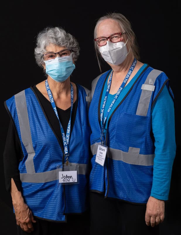 Photo of two people wearing face mask and blue vests