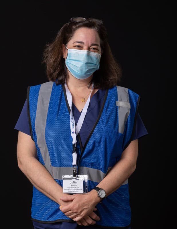 Photo of person wearing face mask and dark blue vest and name tag