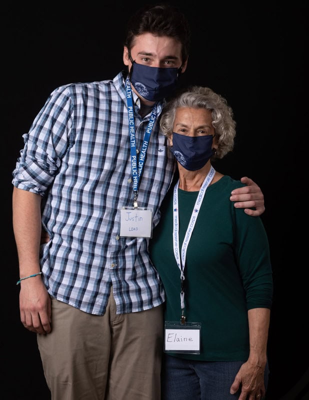 photo of two people hugging each other, wearing face masks and name tags
