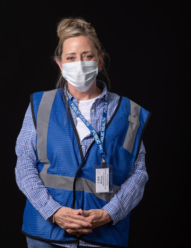 Photo of person wearing face mask, blue vest and name tag