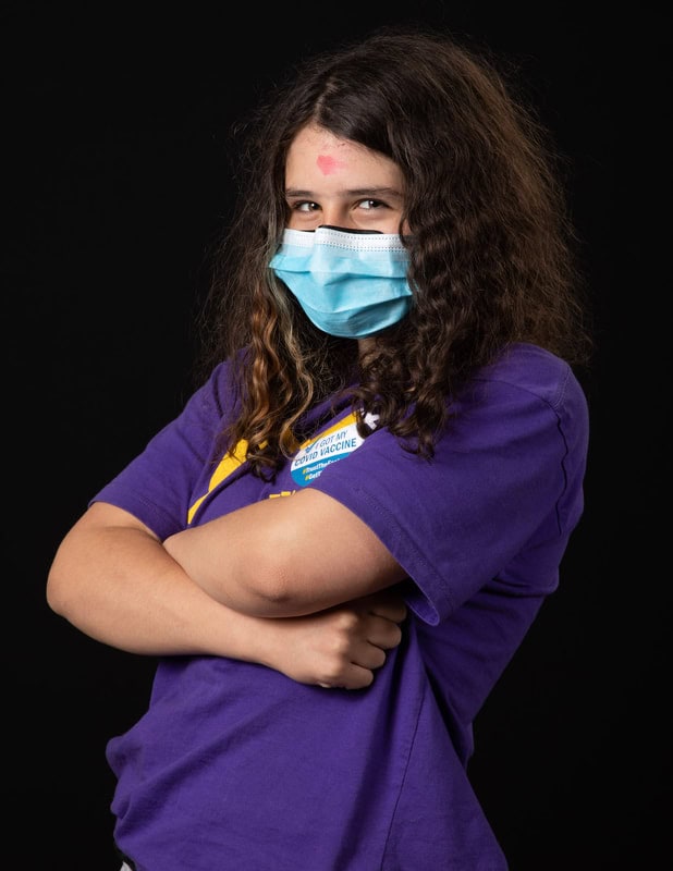photo of person in face mask and purple tshirt with two arms crossed