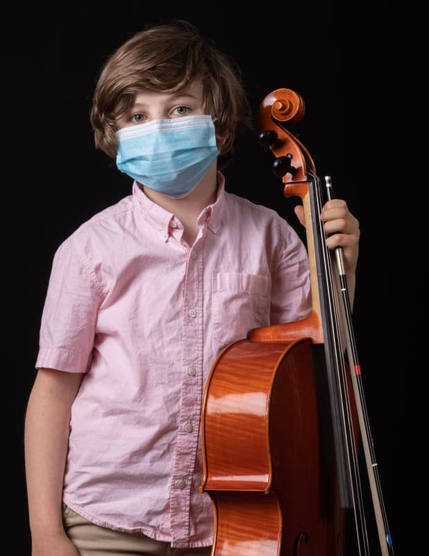 photo of young person wearing face masks and holding a cello