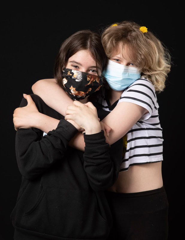 photo of two young people hugging wearing face masks