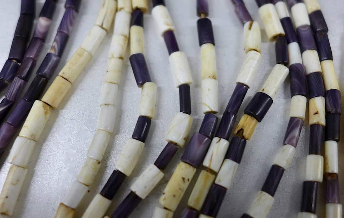 Wampum beads carved from whelk and quahog shells were widely utilized by Northeastern Native people for adornment, exchange, ritual and diplomatic purposes. During the mid-1600s, English and Dutch colonists also used wampum as substitute currency, calculating values in fathoms (6 foot long strands, roughly 240 beads, worth about 5 shillings) and hands (4 inch strings, roughly 24 beads, worth about 6 pence), rather than in pounds, shillings, and pence.